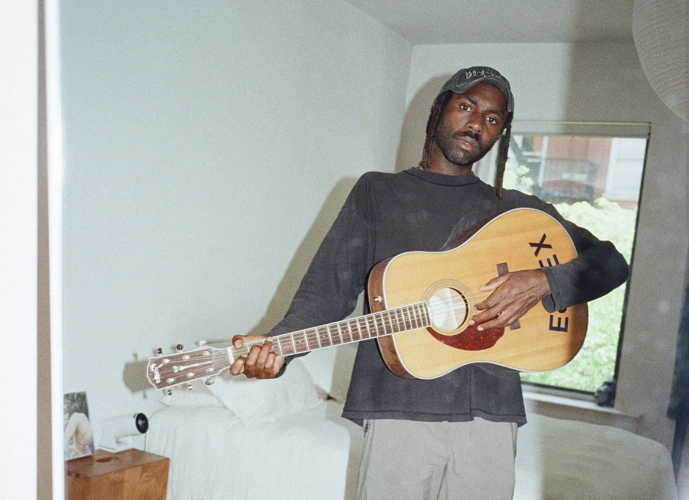 Artisten Blood Orange spiller gitar på soverommet