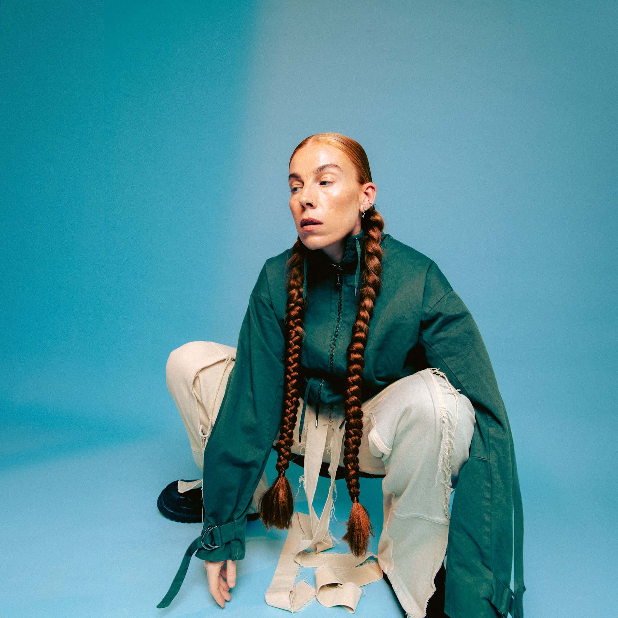 Bilde av artisten Gabrielle som sitter på huk mot blå bakgrunn