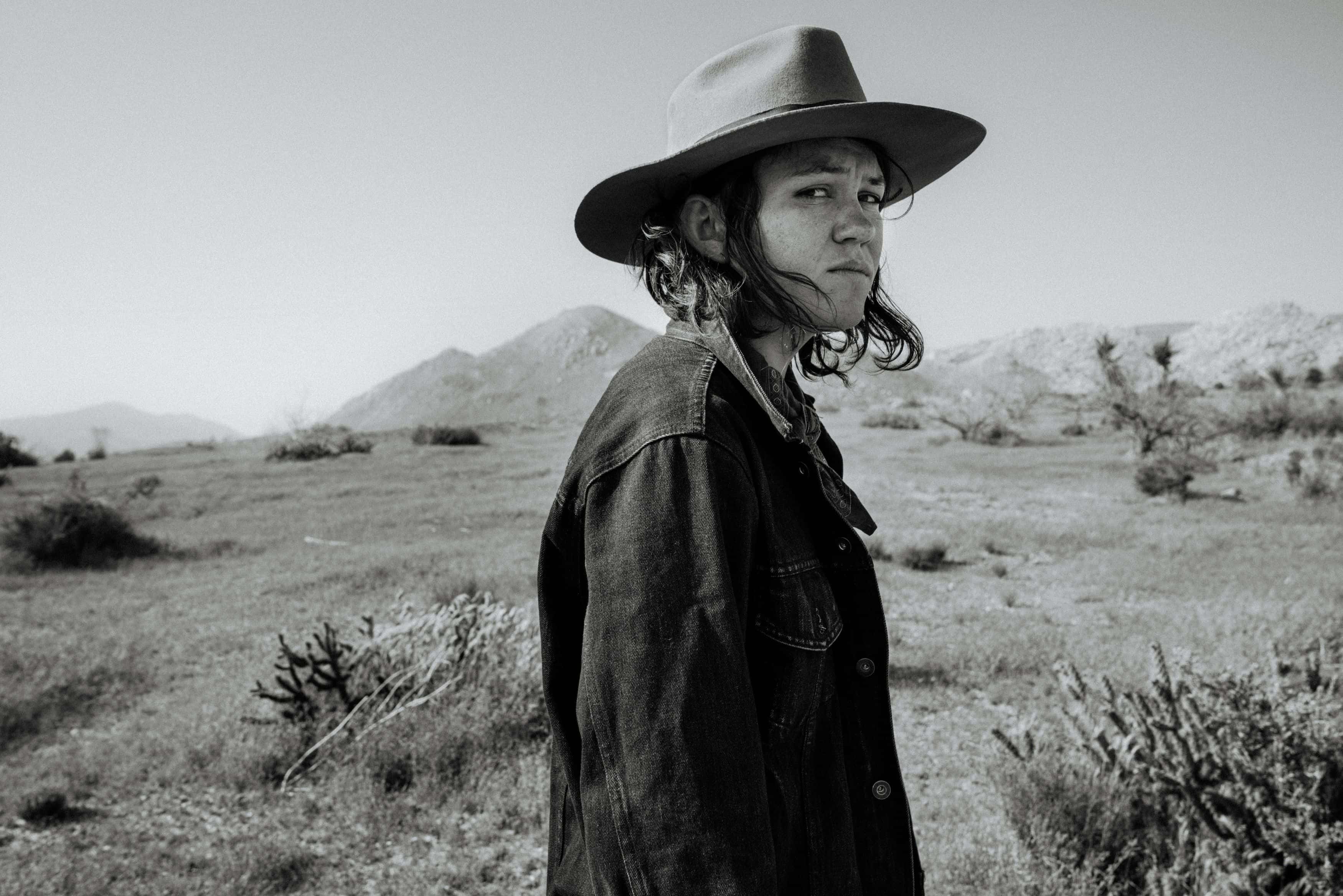 Svart-hvitt foto av artisten Fay Wildhagen, tatt i karrig landskap