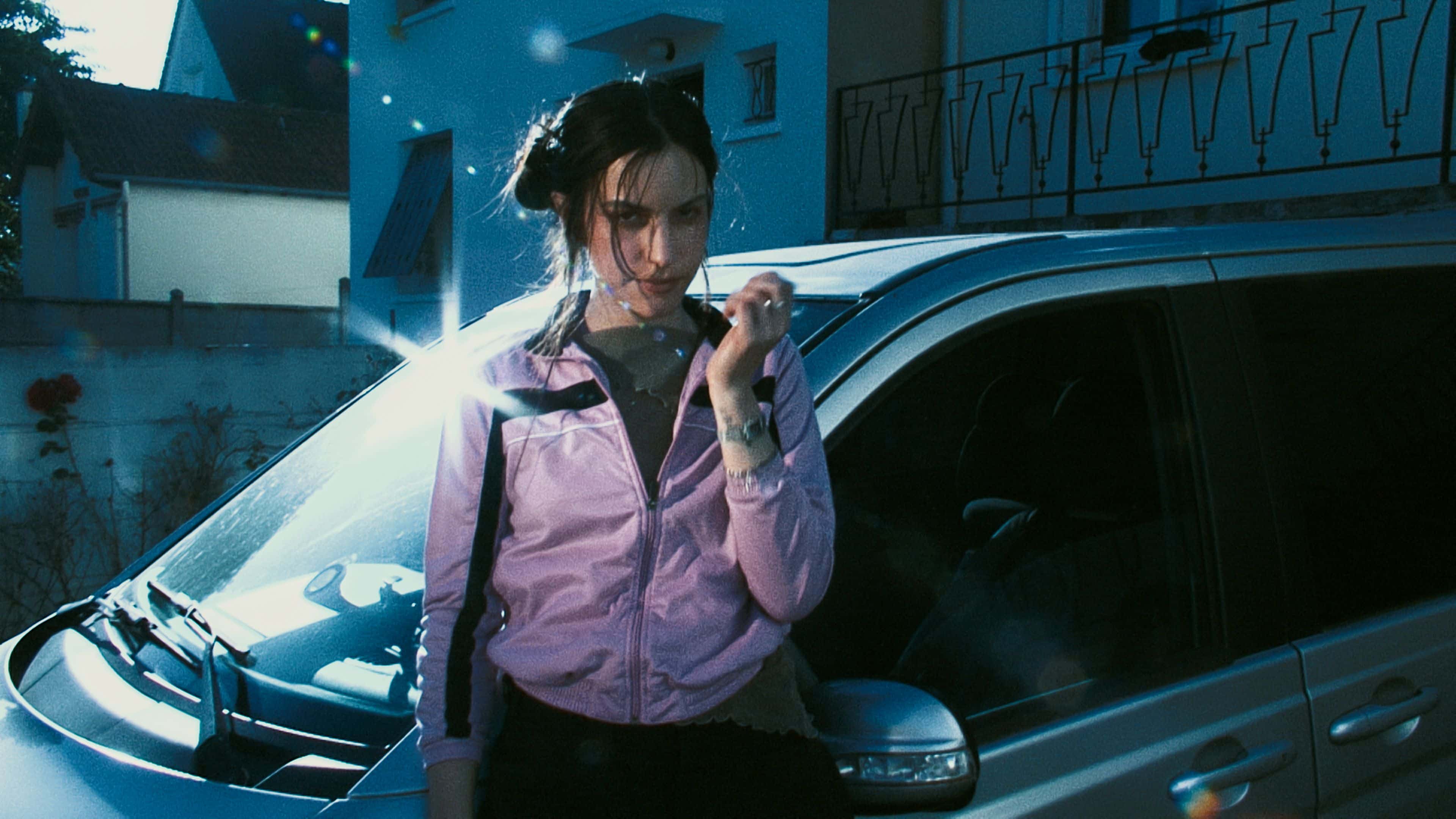 Den franske artisten Oklou, ved siden av en bil