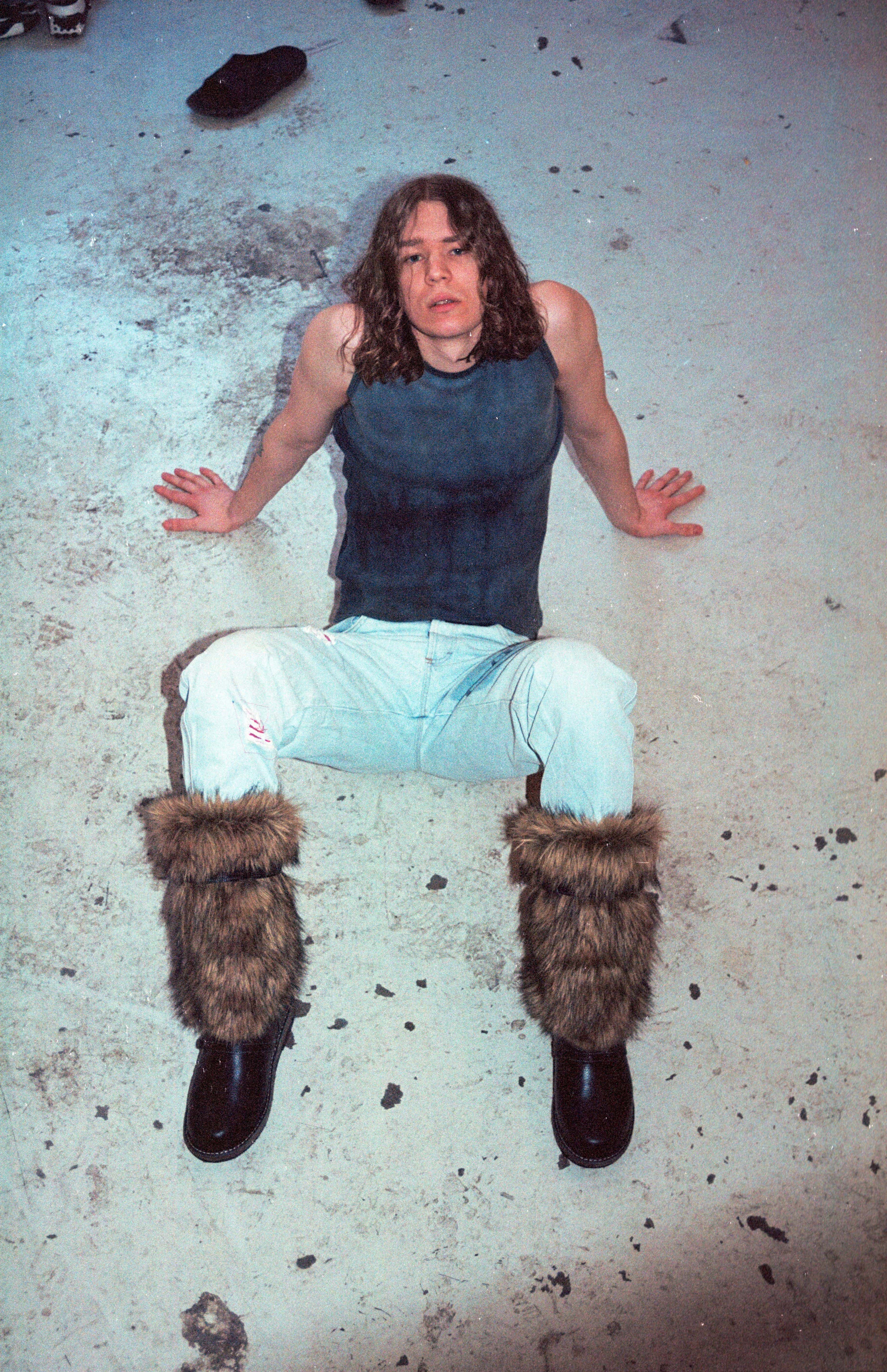 Bilde av artisten Cezinando sittende på et skittent murgulv